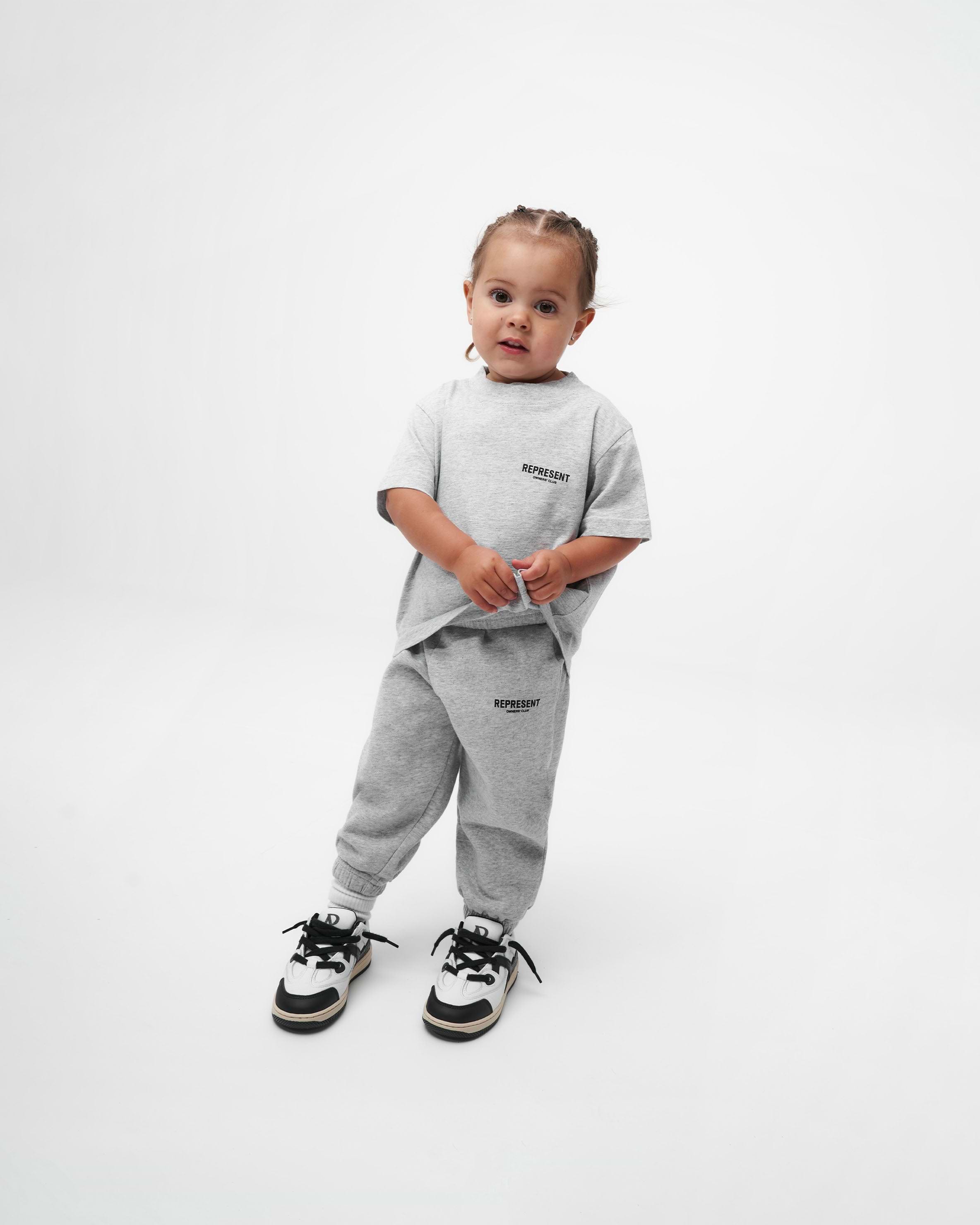 Child wearing grey sweatpants on a plain white background | Represent Mini Owners Club Sweatpants in Ash Grey | Kids sweatpants with elasticated waistband | Owners Club Pants | Represent Clo