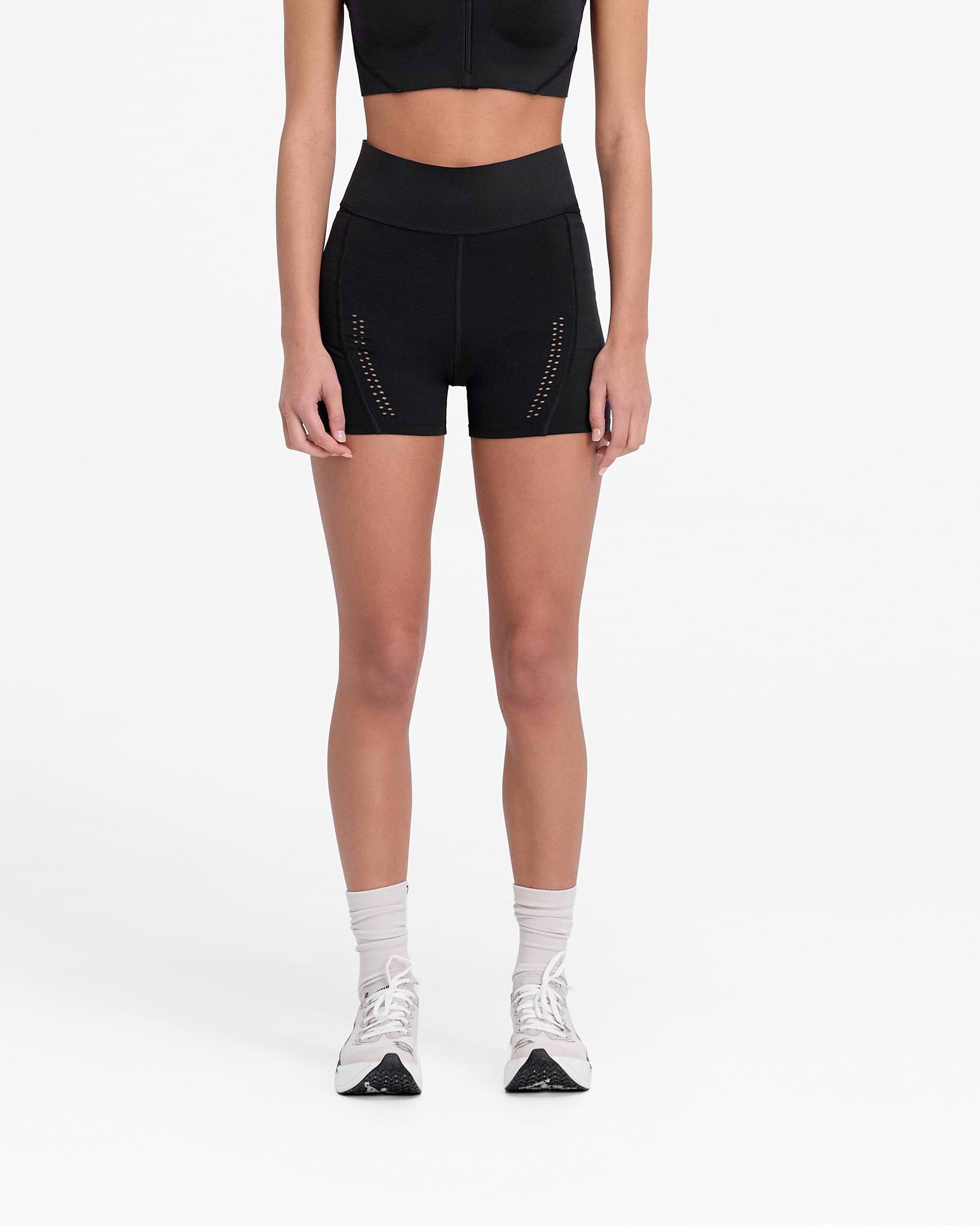 Woman wearing black legging shorts on a plain white background | 247 X Puma Women's Shapeluxe Legging Short in Black | High-waisted performance shorts | 247 Shorts | Represent Clo