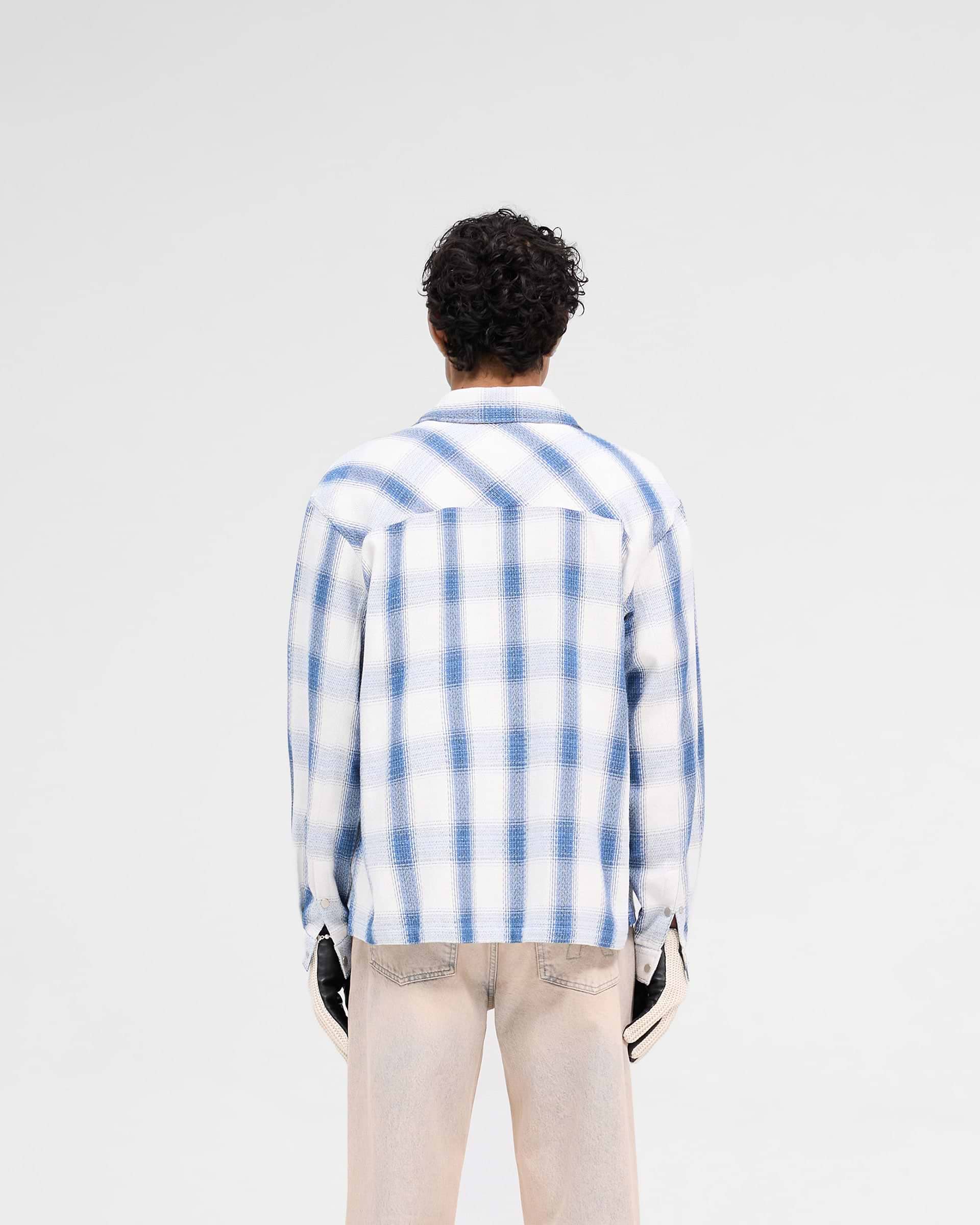 Man wearing a mid blue flannel shirt on a plain white background | Season Flannel Shirt in Mid Blue | Textured flannel shirt with front flap pockets | SS25 Shirts | Represent Clo
