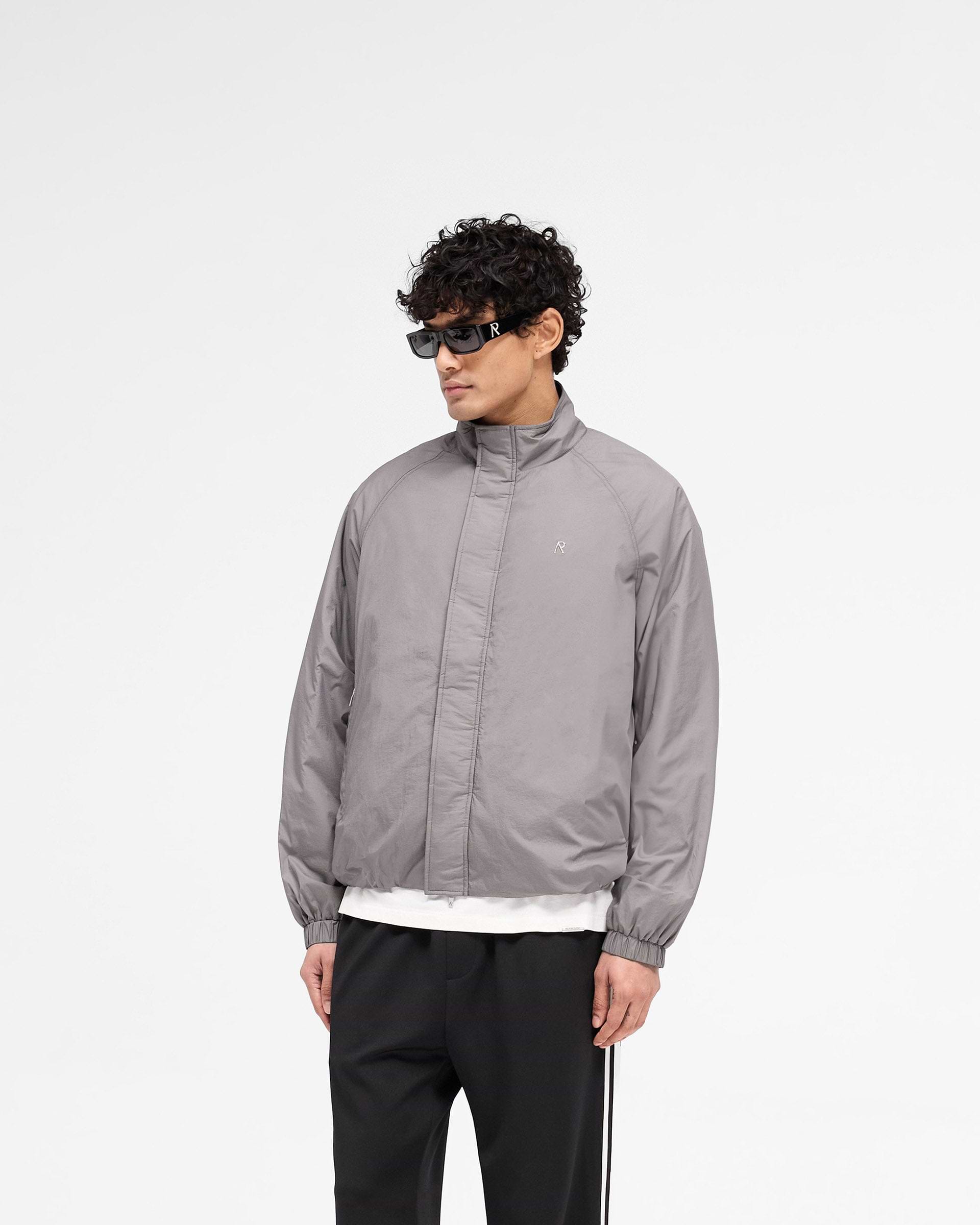 Back product image of a mens stone jacket on a plain white background | Funnel Neck Jacket in Stone | Lightweight outerwear with raglan sleeves and adjustable hem | SS25 Outerwear | Represent Clo