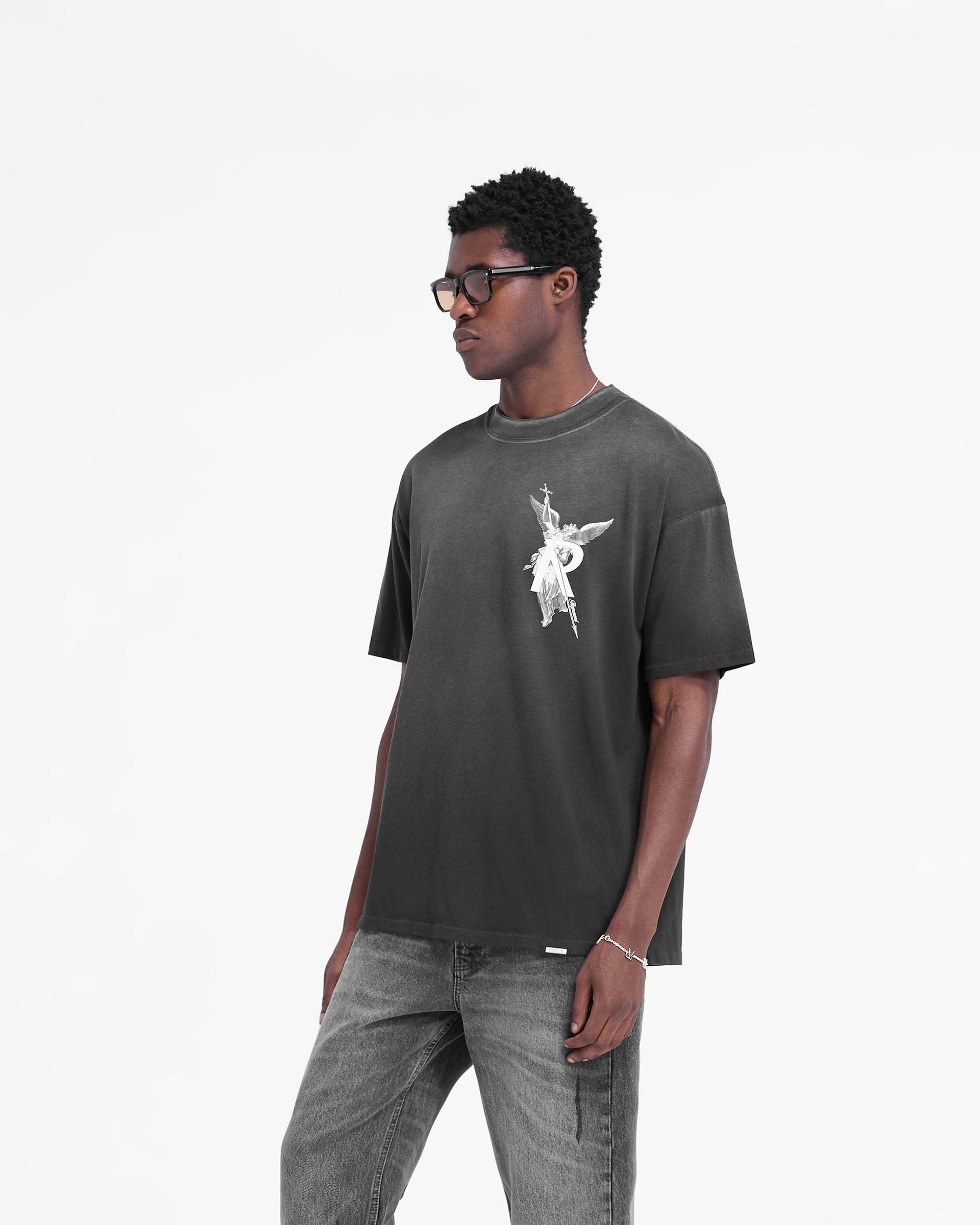 Man wearing a black t-shirt with a graphic on a plain white background | Archangel T-Shirt in Stained Black | Slightly oversized t-shirt with fade out wash | FW24 T-Shirts | Represent Clo