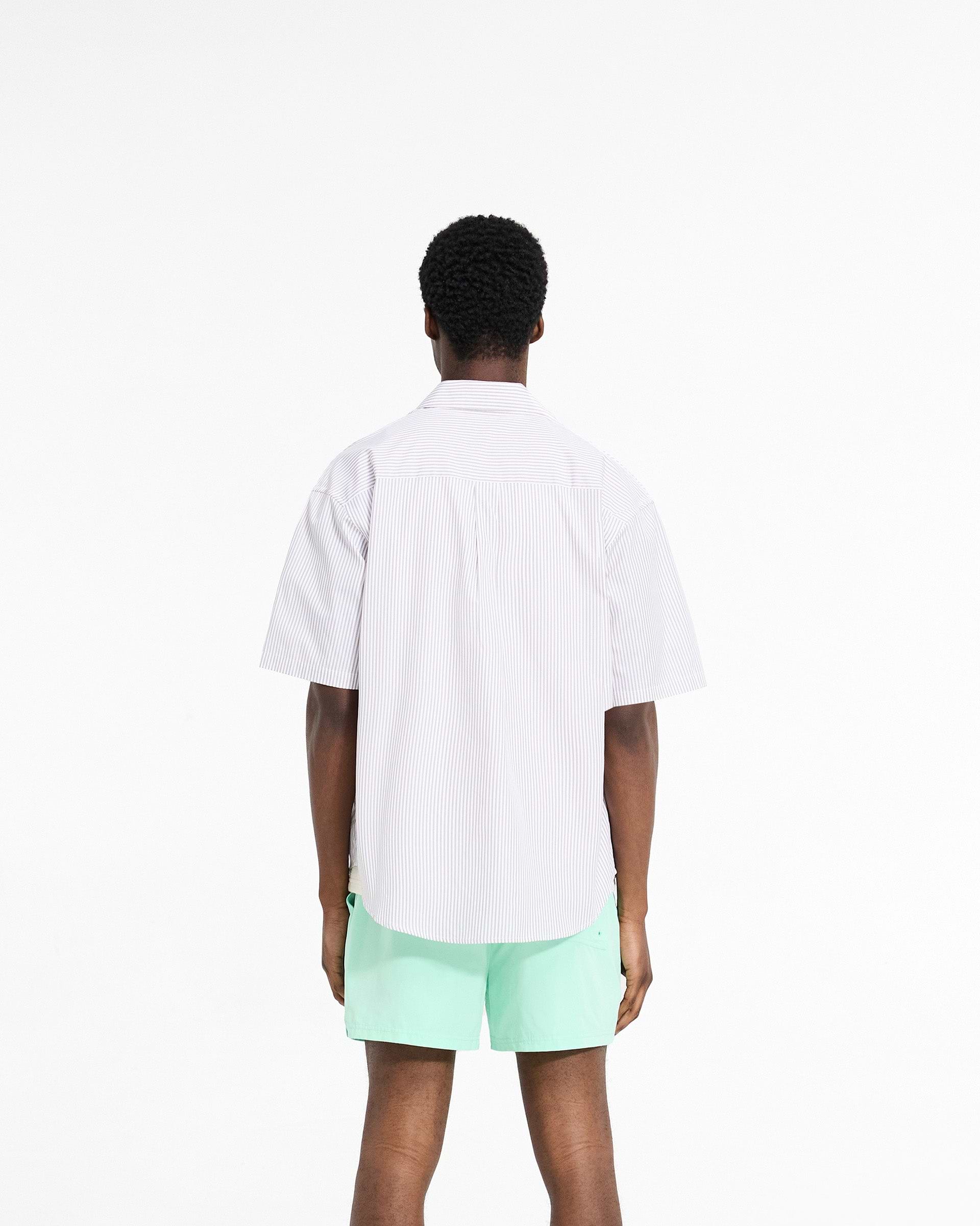 Man wearing a grey pinstripe short sleeve shirt on a plain white background | Short Sleeve Pinstripe Shirt in Grey | Slightly oversized shirt with chest pockets | SC24 Shirts | Represent Clo