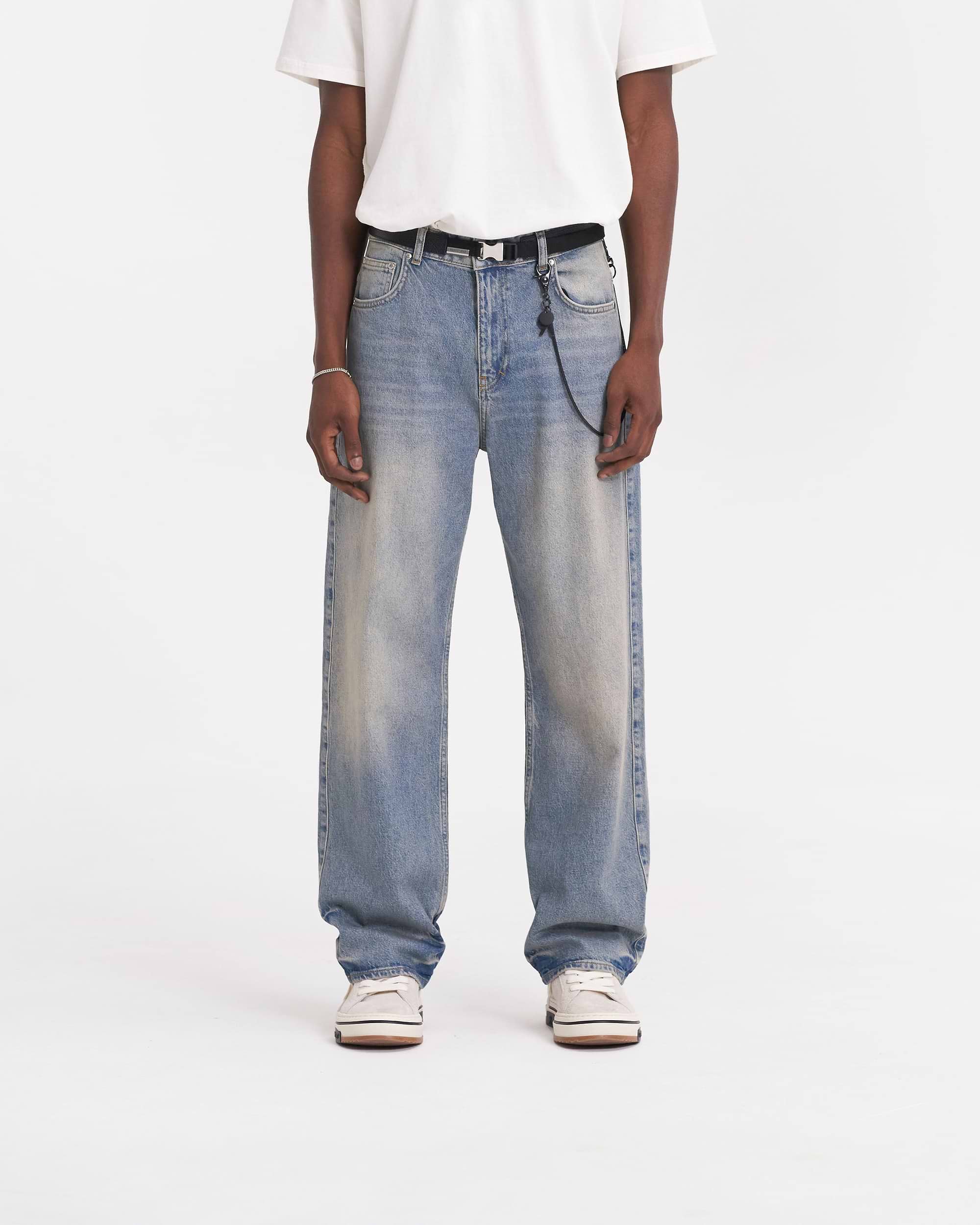 Man wearing blue baggy denim jeans on a plain white background | R3 Baggy Denim in Blue | Relaxed fit denim jeans with soft hand feel | SS24 Denim | Represent Clo