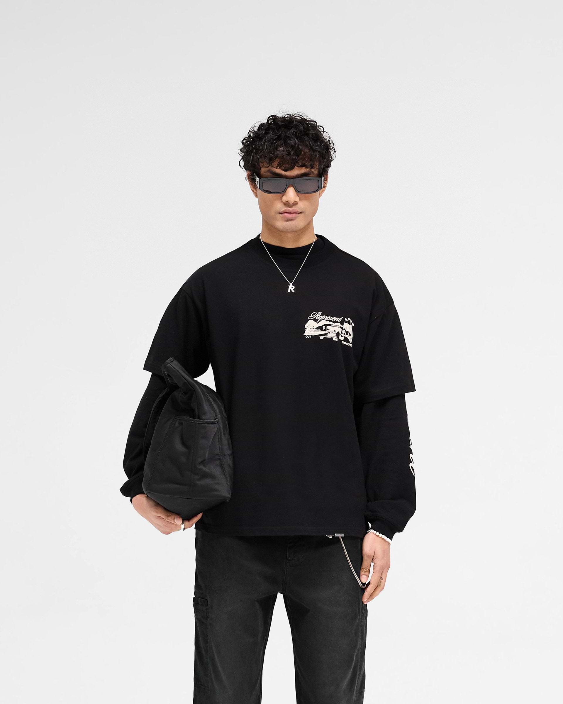 Man wearing a black t-shirt with puff print graphic on a plain white background | Raceway T-Shirt in Jet Black | Slightly oversized t-shirt with metal bar logo | SS25 T-Shirts | Represent Clo