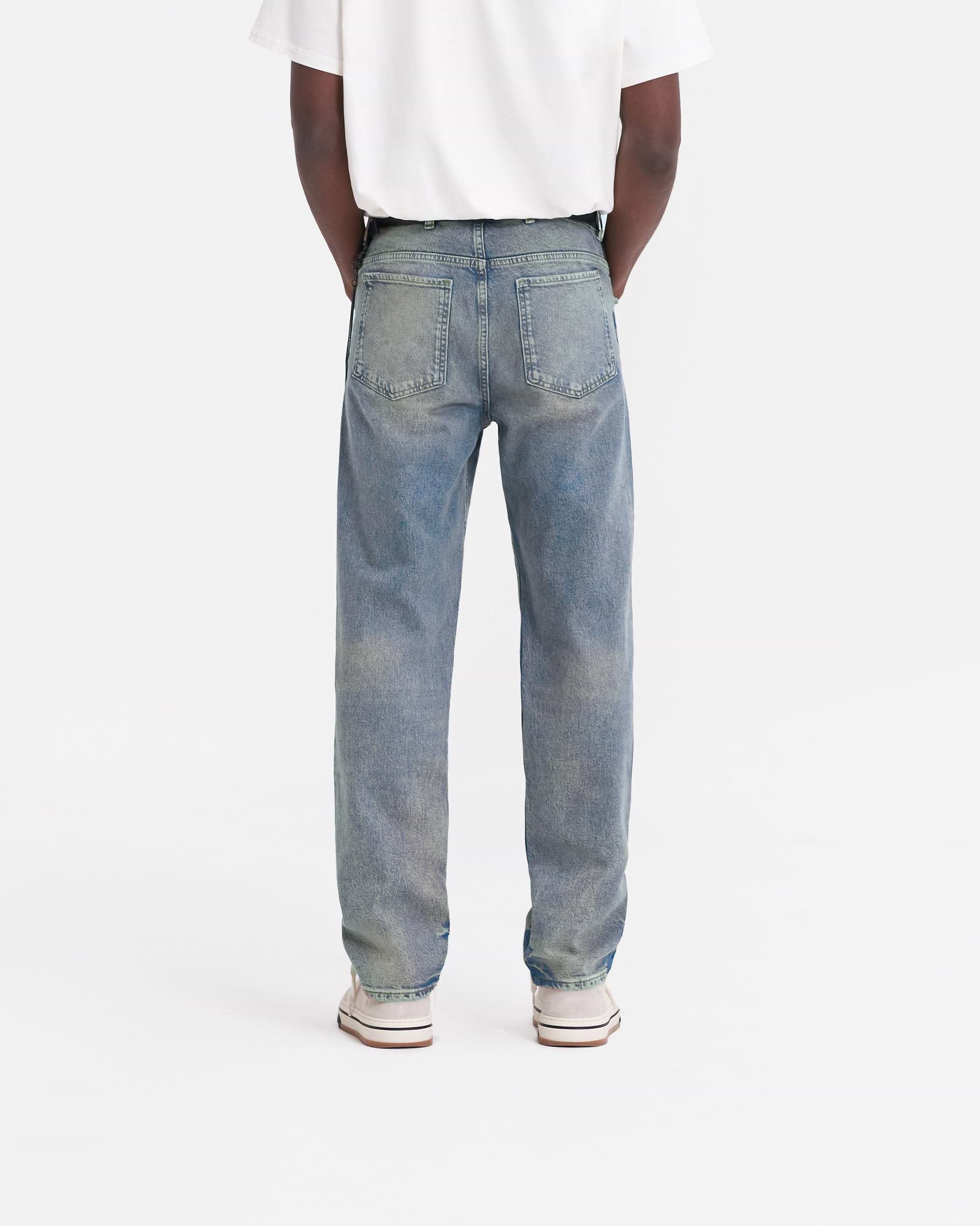 Man wearing blue straight leg jeans on a plain white background | R2 Straight Leg Denim in Blue Cream | Jeans with a zip fly and belt loops | FW23 Denim | Represent Clo
