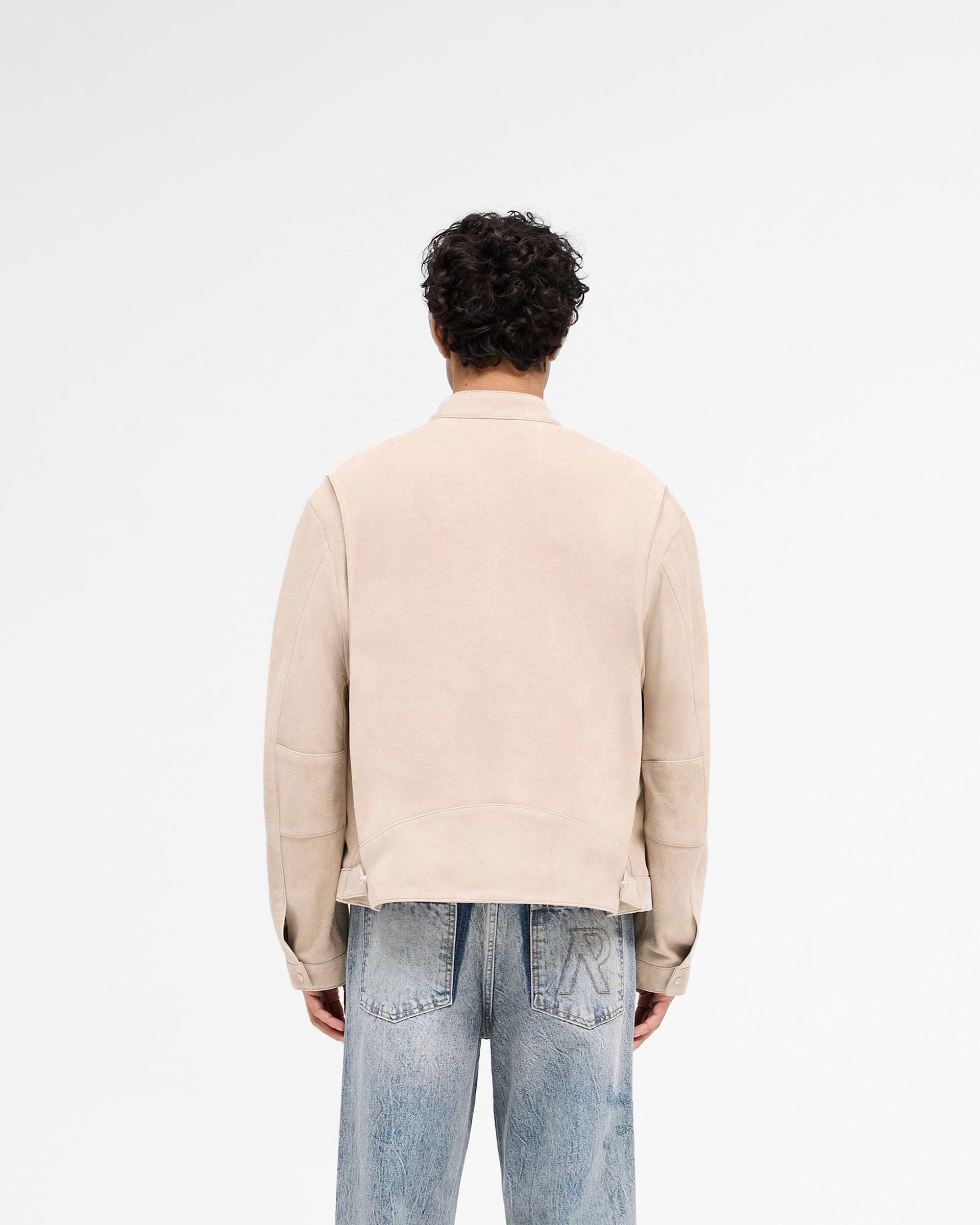 Man wearing a beige suede jacket on a plain white background | Overdrive Suede Jacket in Beige | Suede jacket with biker neck and vented shoulders | SS25 Outerwear | Represent Clo