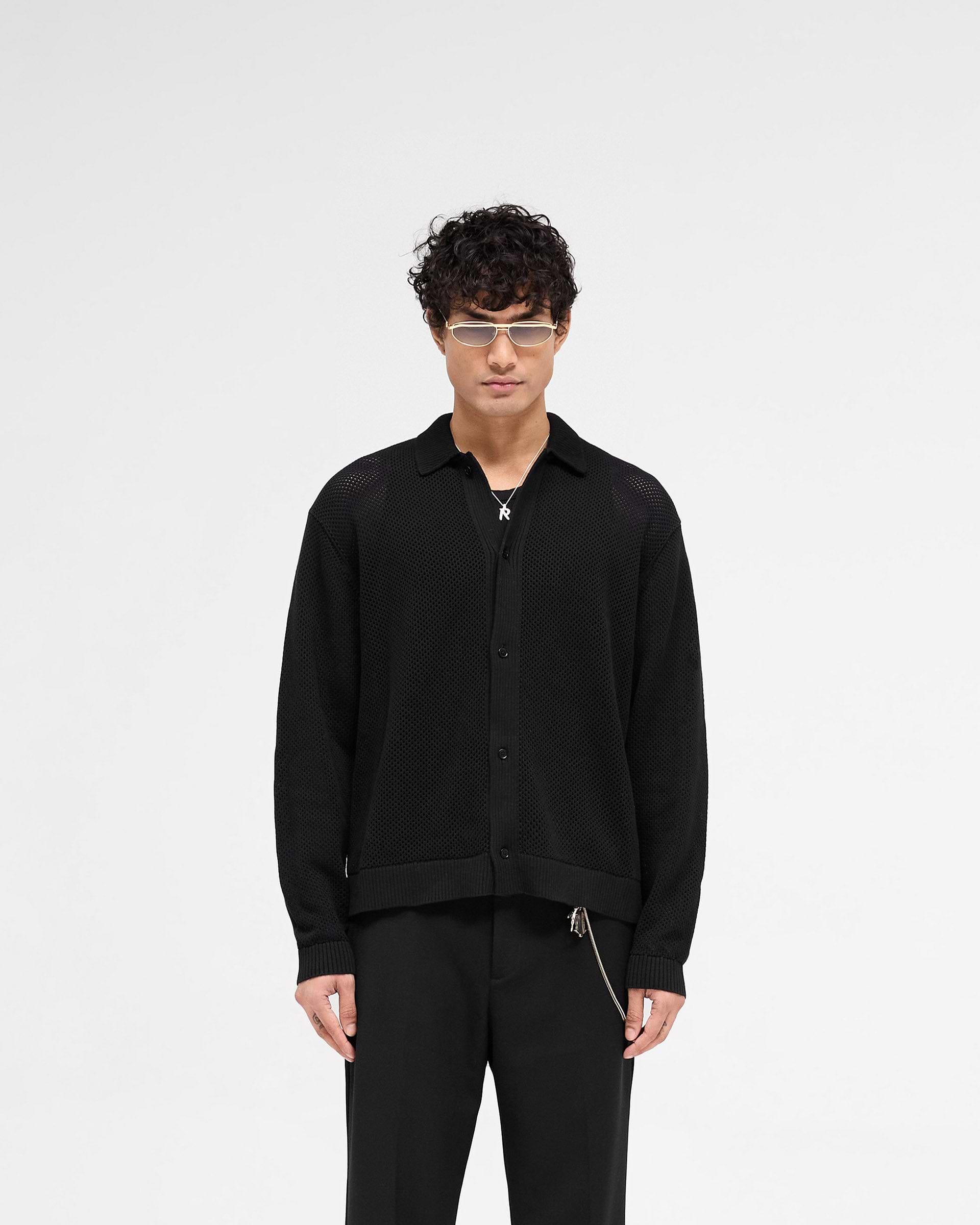 Man wearing a black mesh knit shirt on a plain white background | Long Sleeve Mesh Knit Shirt in Jet Black | Knit shirt with button up and oversized fit | SS25 Knitwear | Represent Clo