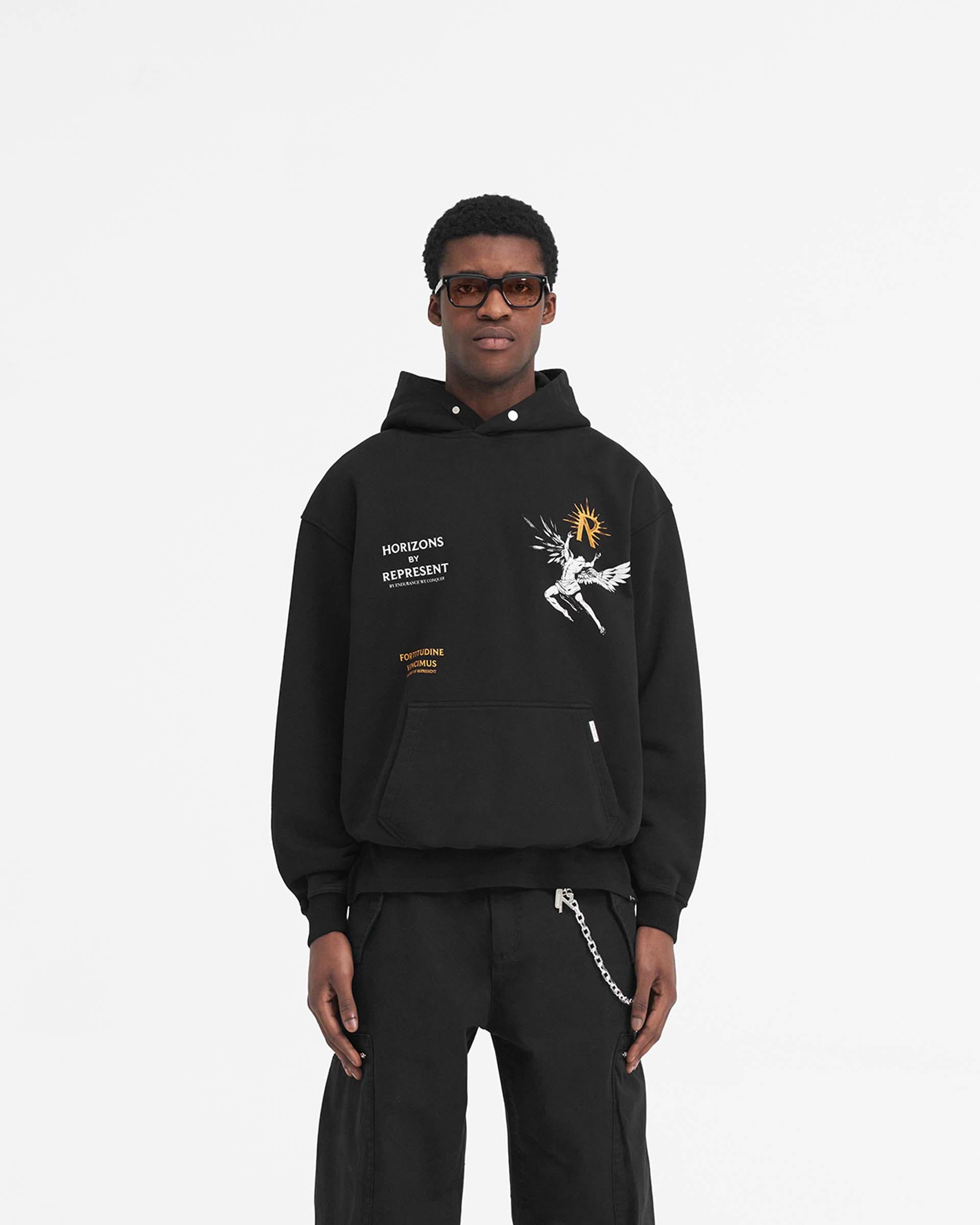 Man wearing an oversized black hoodie on a plain white background | Icarus Hoodie in Jet Black | Oversized hoodie with ribbed hem and Icarus graphic | SS24 Hoodies | Represent Clo