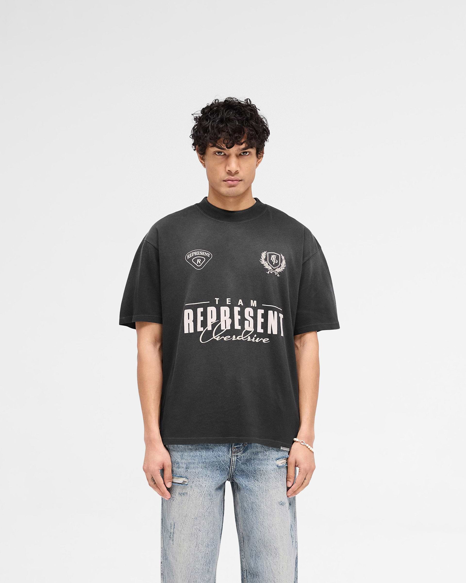 Man wearing a black t-shirt on a plain white background | World Championship T-Shirt in Stained Black | Oversized t-shirt with screen and puff print graphic | SS25 T-Shirts | Represent Clo