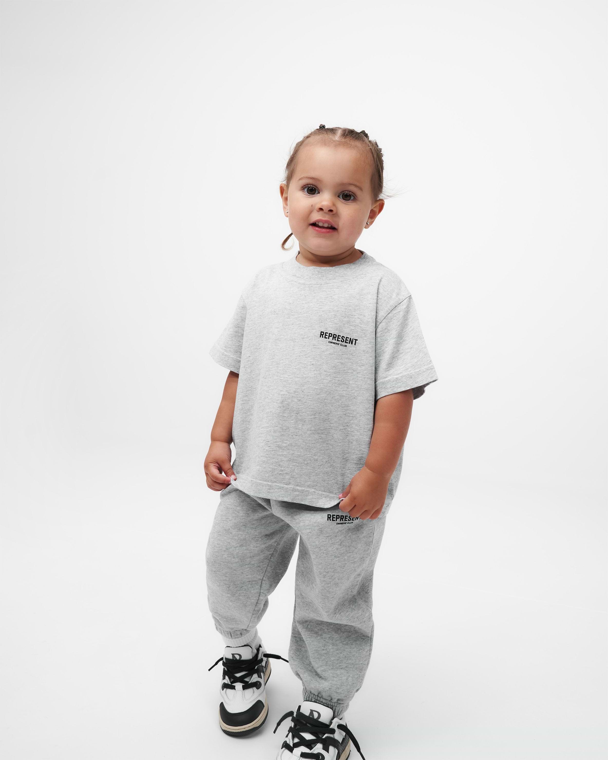 Child wearing an ash grey t-shirt on a plain white background | Represent Mini Owners Club T-Shirt in Ash Grey | Oversized children's t-shirt with screen printed graphic | Owners Club T-Shirts | Represent Clo