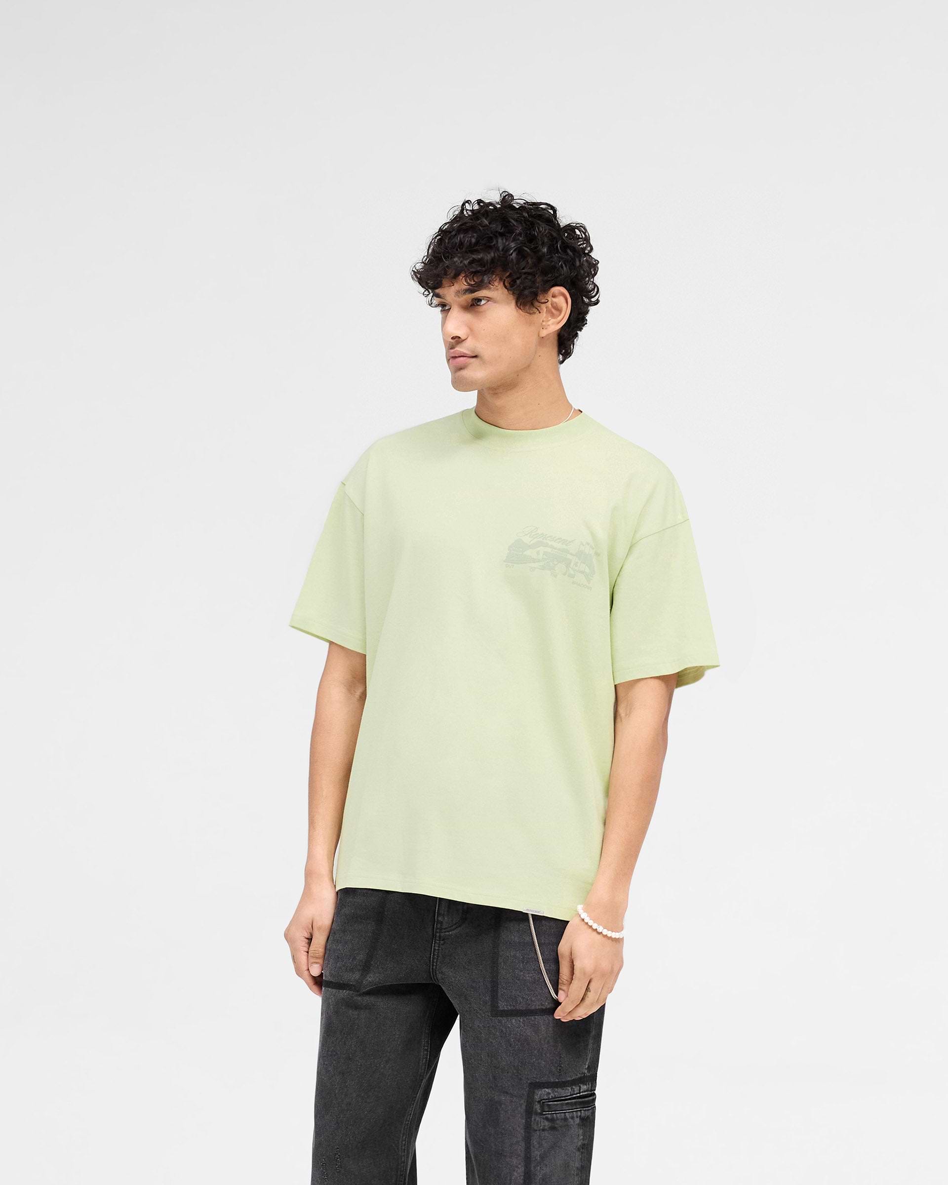 Man wearing a green t-shirt on a plain white background | Raceway T-Shirt in Matcha | Slightly oversized t-shirt with puff print graphic | SS25 T-Shirts | Represent Clo