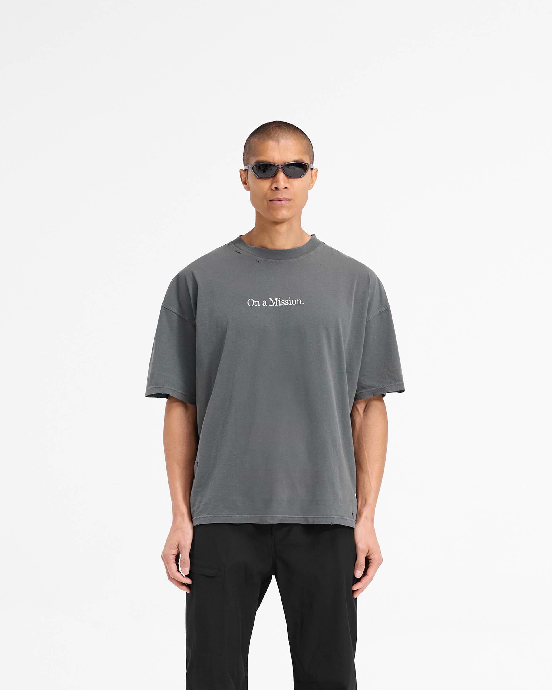 Man wearing an oversized black t-shirt on a plain white background | 247 On A Mission Oversized T-Shirt in Aged Black | T-Shirt with On a Mission embroidery and distressing details | 247 T-Shirts | Represent Clo