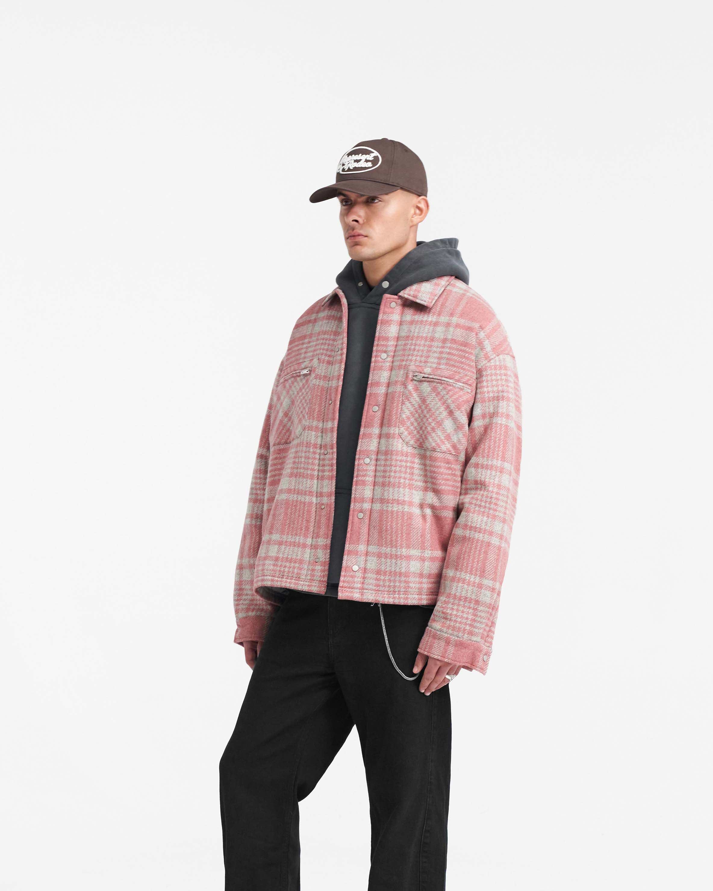 Man wearing a pink grey check flannel shirt on a plain white background | Quilted Flannel Shirt in Pink Grey Check | Quilted shirt with patch zip pockets and split hem | PRE SS24 Shirts | Represent Clo