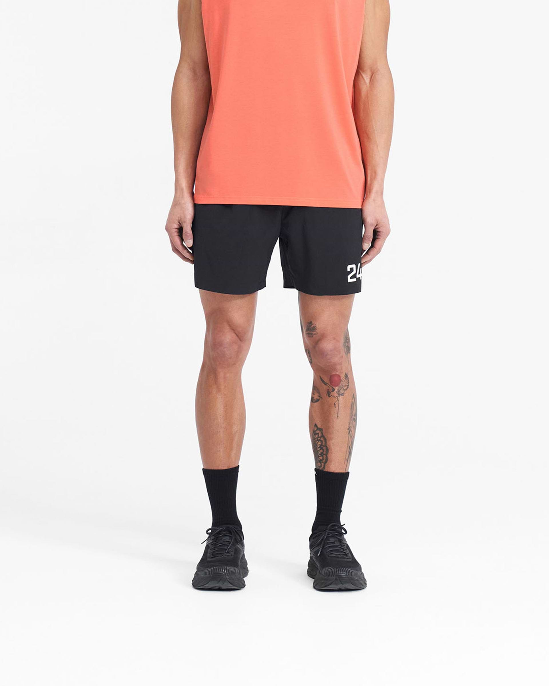 Man wearing black gym shorts on a plain white background | 247 Fused Shorts in Black | Gym shorts with 247 branding and quick-dry fabric | 247 Shorts | Represent Clo