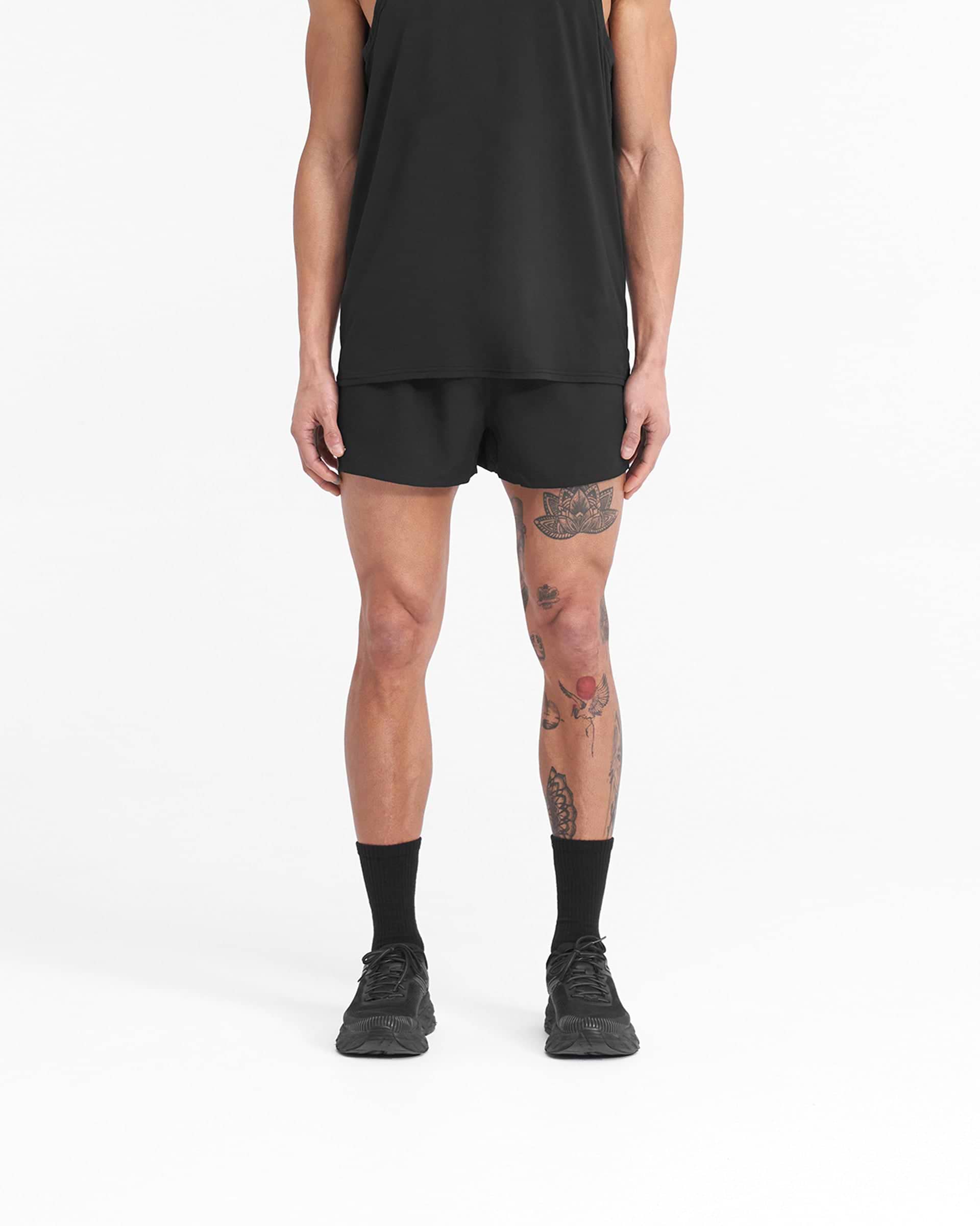 Man wearing black shorts with white details on a plain white background | Team 247 Race Shorts in Jet Black | Polyester shorts with large side splits and zip pocket | 247 Shorts | Represent Clo