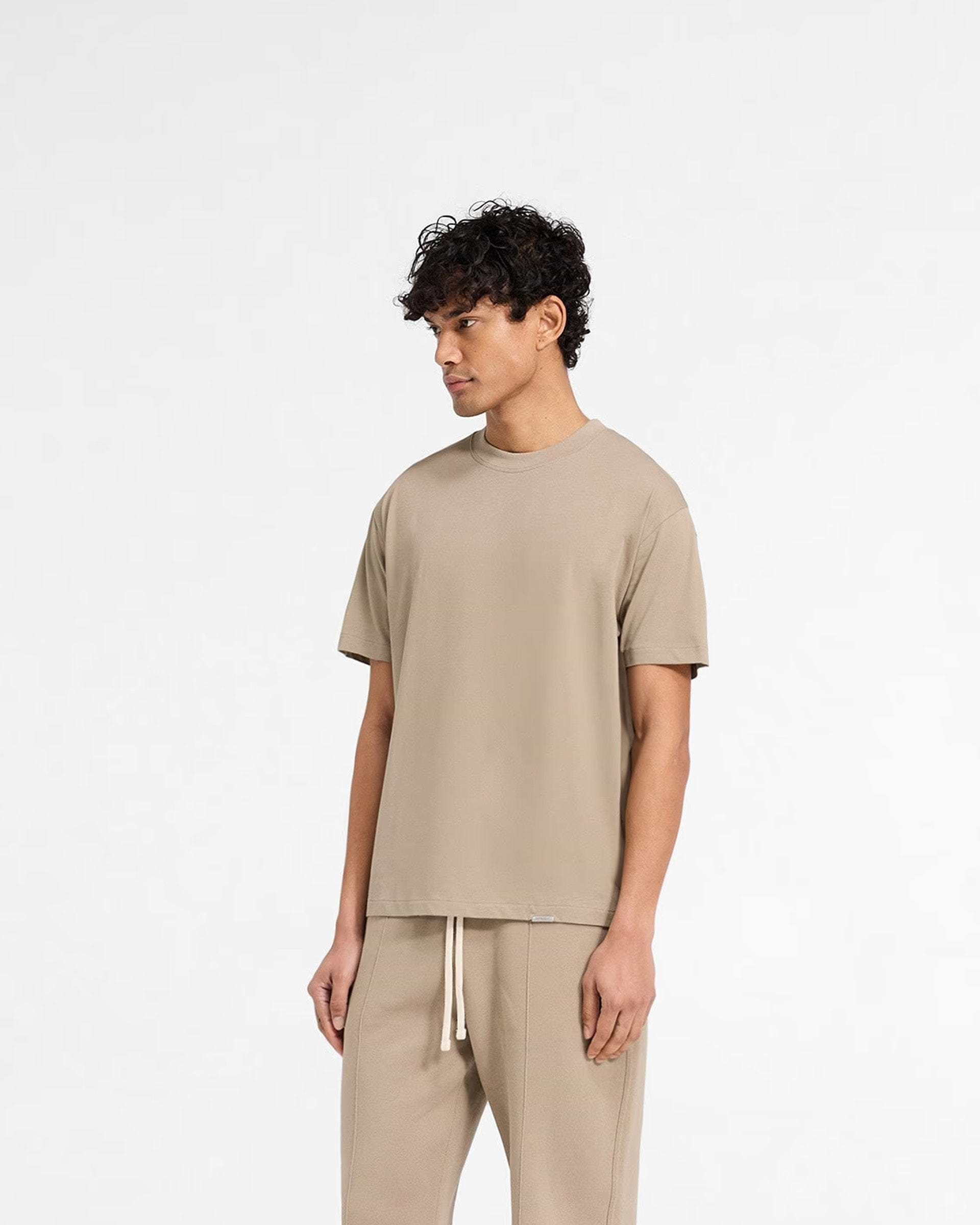Back product image of a mens beige t-shirt on a plain white background | Initial T-Shirt in Dune | Regular fit t-shirt with embroidered back neck detail | Initial T-Shirts | Represent Clo