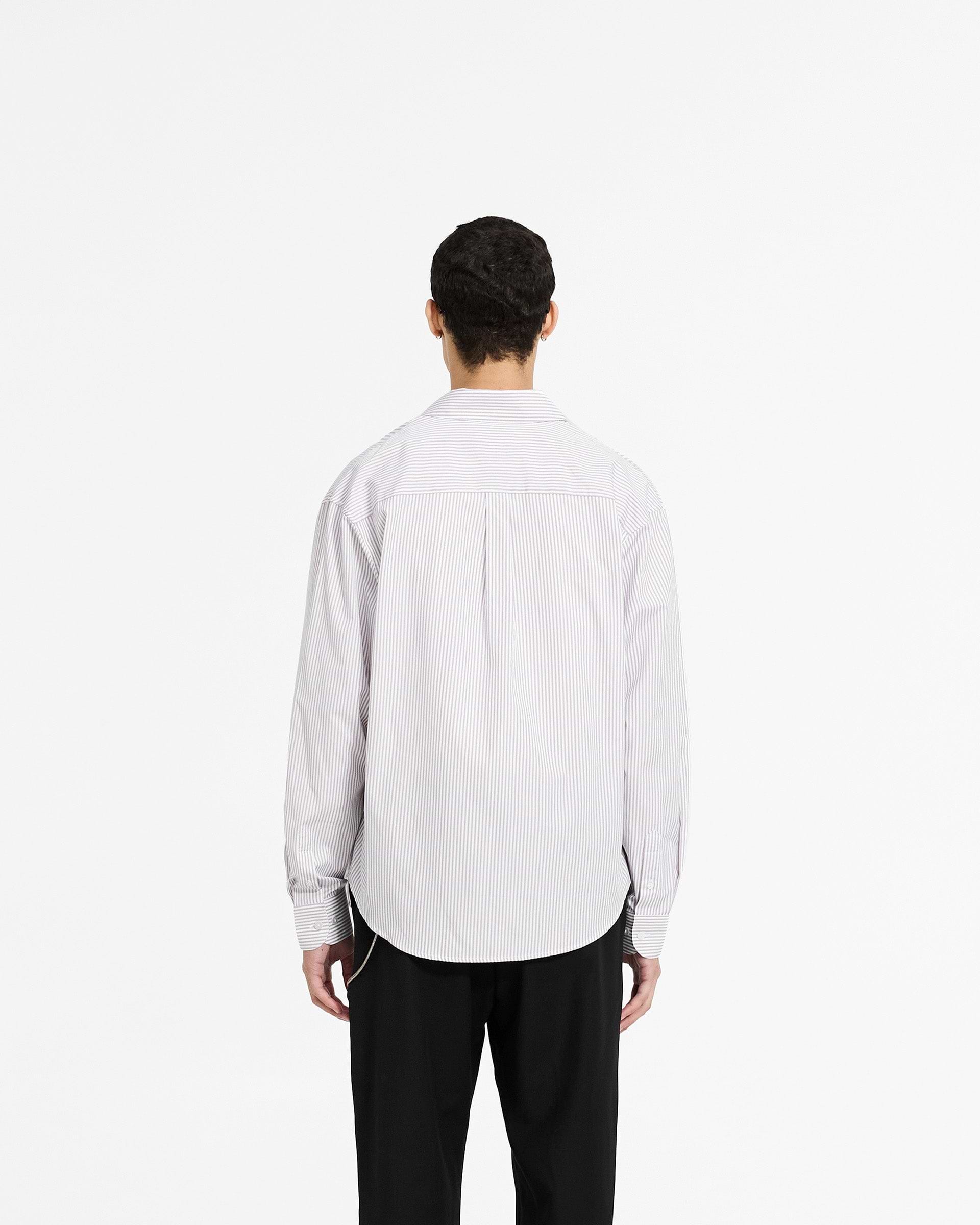 Man wearing a grey pinstripe shirt on a plain white background | Long Sleeve Pinstripe Shirt in Grey | Slightly oversized fit with curved hem | SC24 Shirts | Represent Clo