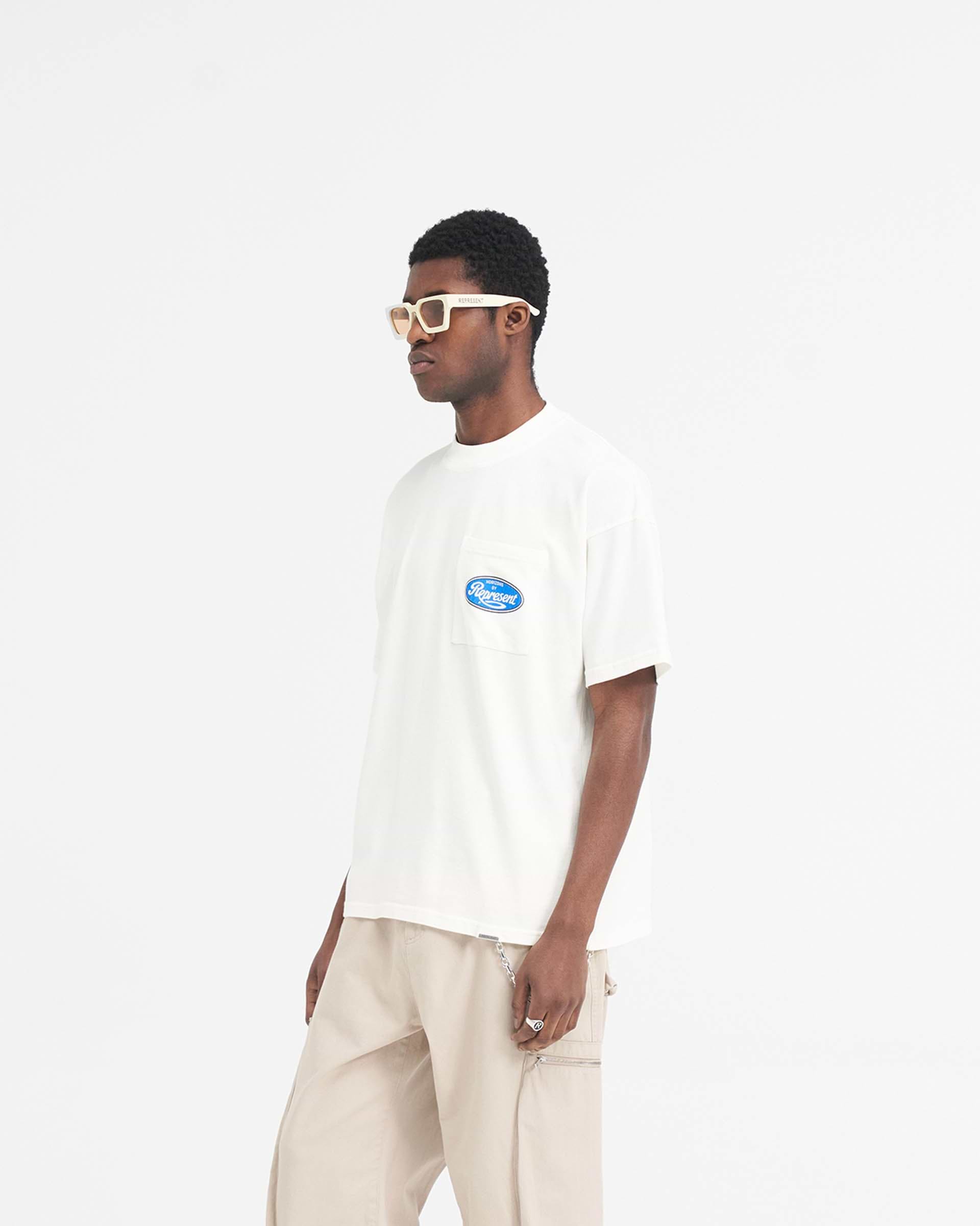 Man wearing an oversized white t-shirt on a plain white background | Classic Parts T-Shirt in Flat White | Oversized t-shirt with Horizons motorsport graphic | SS24 T-Shirts | Represent Clo