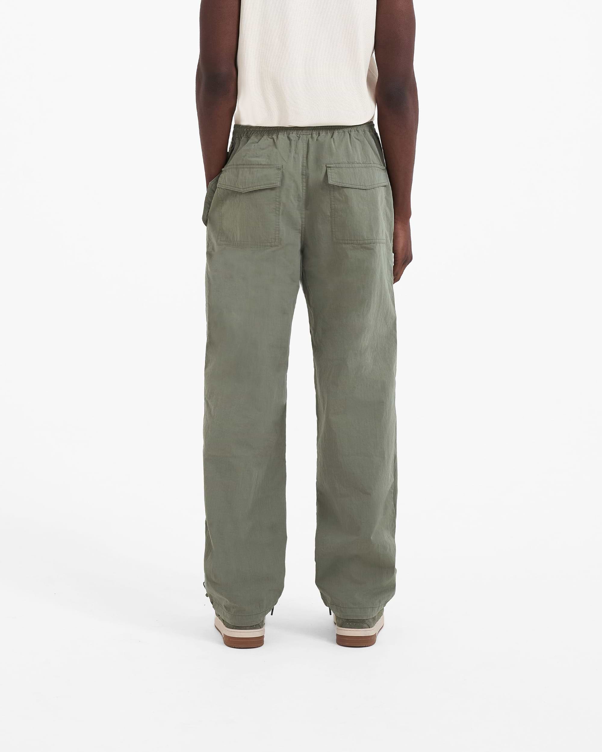Man wearing khaki pants on a plain white background | Parachute Pant in Khaki | Baggy fit pants with elasticated waistband and drawstring | SC23 Pants | Represent Clo
