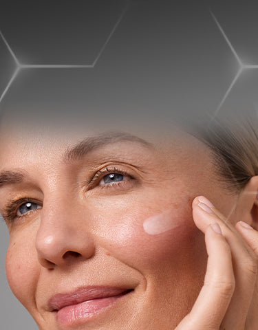 A professional web banner for the Medik8 regime builder. At the top, there is a dark grey gradient background with a subtle white hexagonal pattern. At the bottom, there is a close-up of a woman with glowing skin applying a cream to her cheek. Text reads 'Build Your Tailored Skincare Regime' with a call-to-action button labelled 'BUILD MY REGIME'.