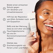 Die Tube der Medik8 Advanced Day Ultimate Protect Creme wird von einem lächelnden Model gehalten, mit einem Auftrag weißer Creme auf ihrer Wange vor warmem beigem Hintergrund. Der Text hebt vier Hauptvorteile hervor: kraftvoller Schutz vor UV-Strahlen und Umweltstressoren, Reparatur von DNA-Schäden nach UV-Exposition, 94 % stimmen zu, dass sie sich wie eine Feuchtigkeitscreme anfühlt, und 100 % erlebten kein Abrollen oder Pilling.