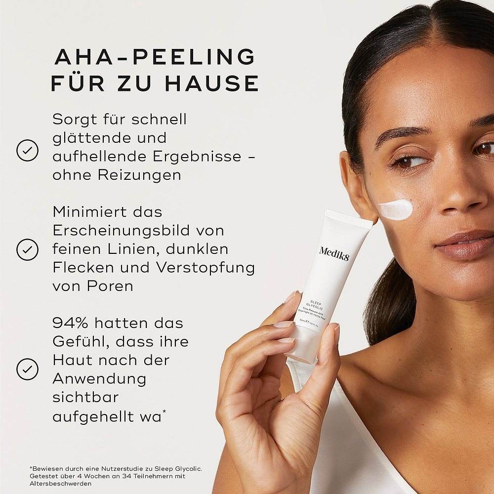 Eine Person hält eine Medik8 Sleep Glycolic-Tube vor einem neutralen, off-weißen Hintergrund, mit einem Strich weißer Creme auf ihrer Wange. Der Text hebt die Vorteile als „At-Home AHA Peel“ hervor, das „schnell glättende und aufhellende Ergebnisse liefert – ohne Reizungen“ und „das Erscheinungsbild feiner Linien, dunkler Flecken und Unreinheiten minimiert.“ Es wird außerdem angegeben: „94 % empfanden, dass ihre Haut nach der Anwendung sichtbar strahlte.“