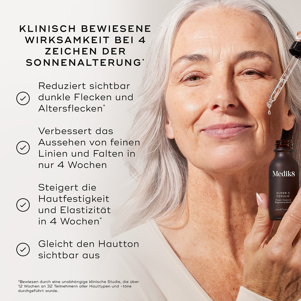 Eine Nahaufnahme einer lächelnden Frau, die eine Tropfflasche mit dem „Medik Super C Ferulic Serum“ vor einem hellen Hintergrund in der Hand hält, begleitet von einem Text über die sichtbare Reduzierung von Sonnenschäden und die Verbesserung der Hautelastizität.