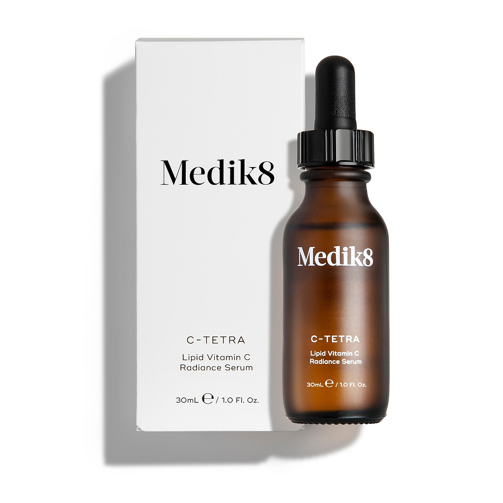 Eine 30-ml-Bernsteinflasche des Medik8 C-Tetra Lipid Vitamin C Radiance Serums vor seiner schlichten, weißen Kartonverpackung.