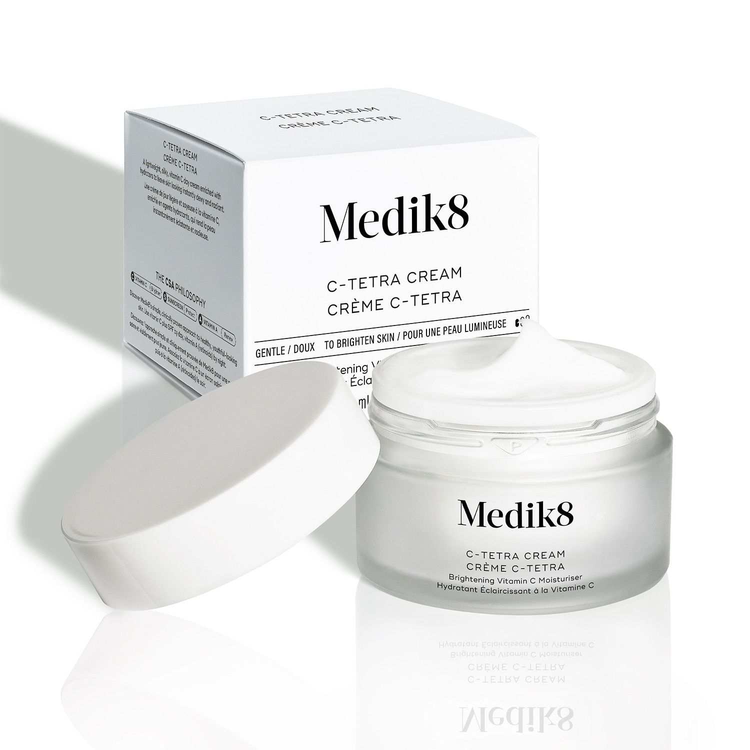 Das Medik8 C-Tetra Cream Glasgefäß und sein weißer Karton stehen auf sauberem weißem Hintergrund mit weichen Schatten. Das offene, weiße, satiniertes Glasgefäß trägt das Medik8-Logo und ist als C-TETRA CREAM Lipid Vitamin C Radiance Cream in 50 mL gekennzeichnet. 