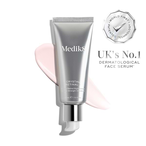 Es ist eine silberne Tube „Crystal Retinal 1“ abgebildet, rechts davon ein rosa Farbmuster der Creme. Außerdem sind ein Siegel mit der Aufschrift „WELTWEIT ERSTE PATENTIERTE TECHNOLOGIE“ und ein Symbol mit der Aufschrift „VON DERMATOLOGEN EMPFOHLEN“ zu sehen.