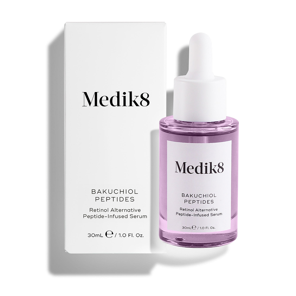 La botella del sérum Medik8 Bakuchiol Peptides, llena de líquido morado, se encuentra junto a su caja exterior blanca sobre un fondo blanco limpio. El texto del envase lo identifica como un “Sérum con péptidos, alternativa al retinol”.