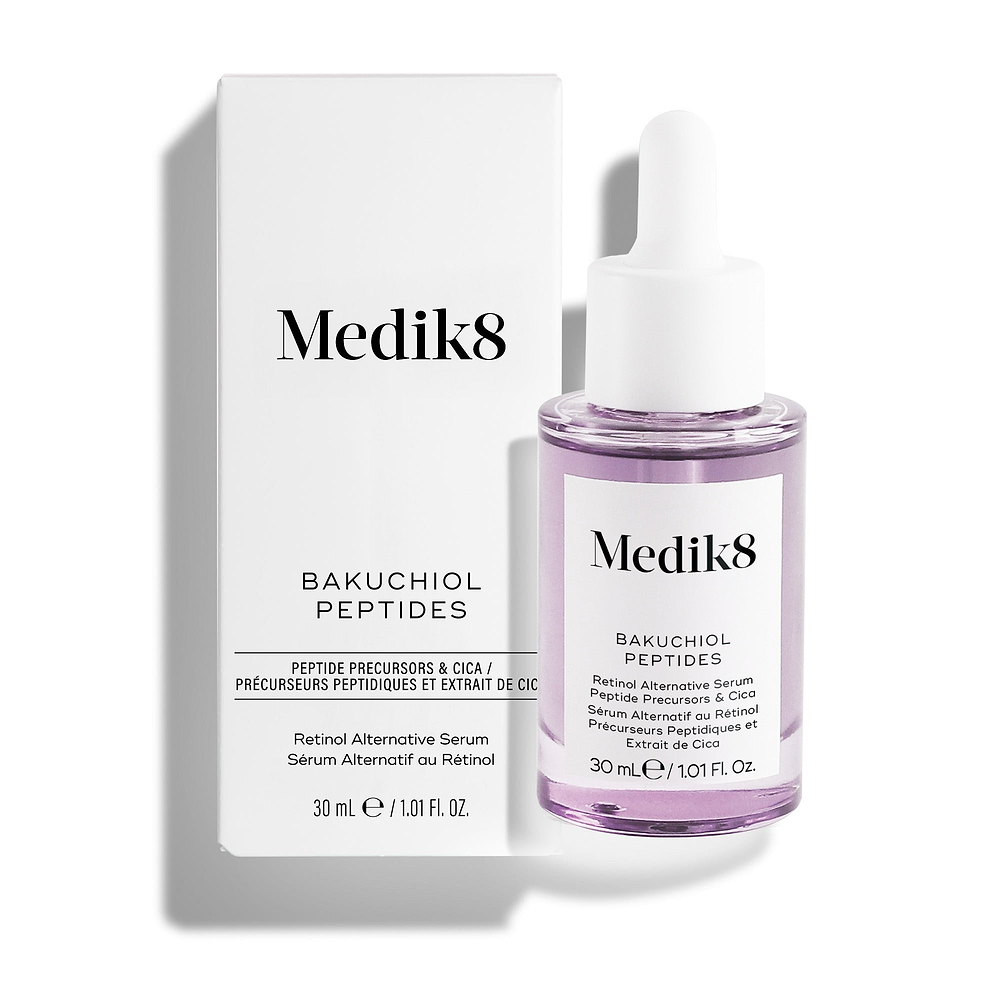 Sérum «Bakuchiol Peptides Retinol Alternative» de Medik8, que se muestra con su caja de embalaje blanca y un frasco cuentagotas transparente que contiene un líquido de color morado claro, sobre un fondo blanco impecable.