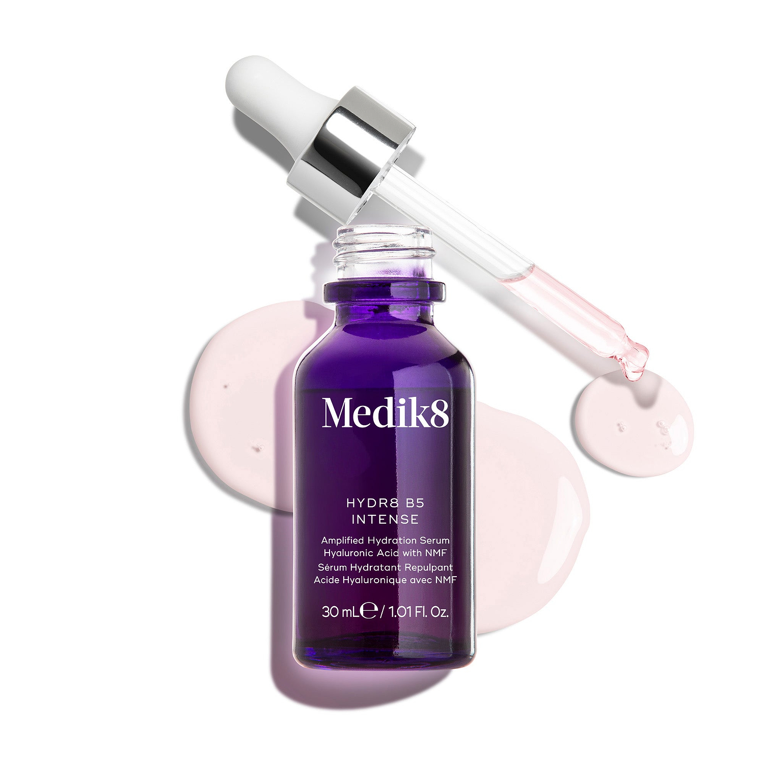 Un frasco cuentagotas de vidrio de Medik8 Hydr8 B5 Intense en color púrpura intenso, mostrado con una pipeta abierta colocada sobre gotas de sérum rosa claro sobre un fondo blanco limpio. El texto destaca la fórmula como ácido hialurónico con NMF (factores naturales de hidratación) para reponer y potenciar, en tamaño de 30 ml.