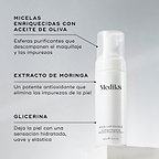 Una botella de Medik8 Micellar Mousse exhibida sobre un bloque blanco. Unas líneas conectan la botella con texto que explica los ingredientes clave: micelas infusionadas con aceite de oliva para descomponer el maquillaje, extracto de moringa para extraer las impurezas y glicerina para proporcionar hidratación.