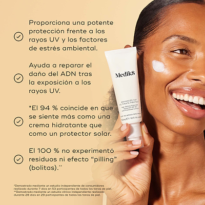 Un modelo sonriente sostiene el tubo de Medik8 Advanced Day Ultimate Protect con una muestra de crema blanca en la mejilla sobre un fondo beige cálido. El texto destaca cuatro beneficios clave: protección avanzada contra los rayos UV y los factores de estrés ambiental, reparación del daño en el ADN tras la exposición a los rayos UV, el 94 % está de acuerdo en que se siente como una crema hidratante y el 100 % no experimentó formación de grumos ni efecto “pilling”.
