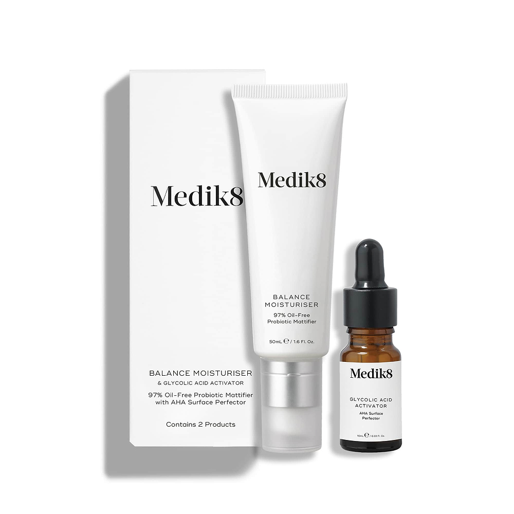 A white cardboard box stands next to a white tube of Balance Moisturiser and a small brown glass bottle of Glycolic Acid Activator.