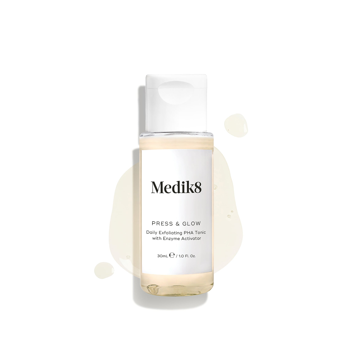 Medik8 Press & Glow tonic bottle stands against a clean white background with translucent liquid droplets and a puddle, highlighting its watery texture. Text identifies the product as a 30ml "Daily Exfoliating PHA Tonic with Enzyme Activator."