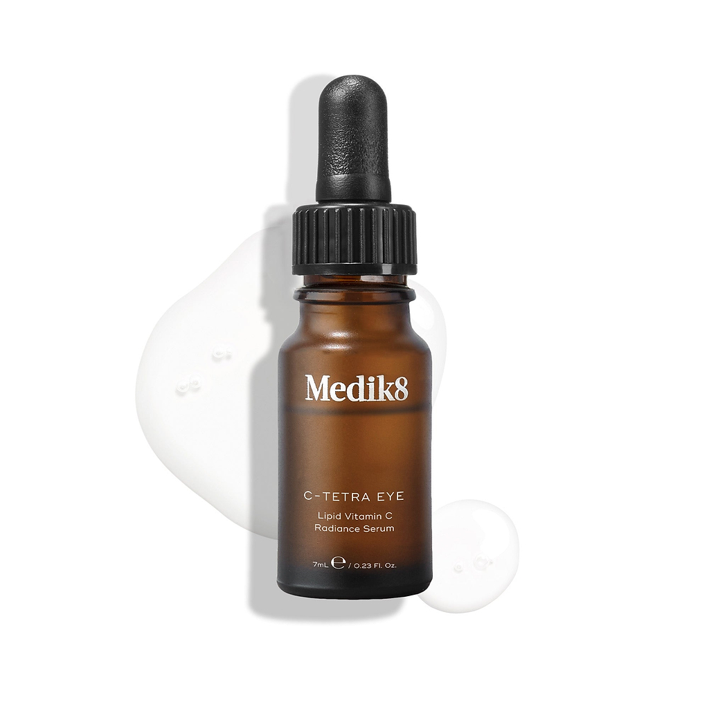 Flacon de Medik8 C-Tetra Eye Lipid Vitamin C Radiance Serum présenté sur un fond blanc avec des gouttes de sérum translucides mettant en valeur sa texture liquide
