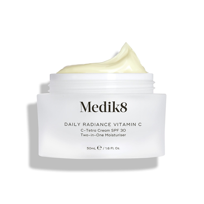 Pot de verre Medik8 Daily Radiance Vitamin C ouvert avec un généreux pic de crème jaune pâle sur le dessus. Le texte identifie le produit comme un C-Tetra Cream SPF 30 Two-in-One Moisturiser de 50 mL