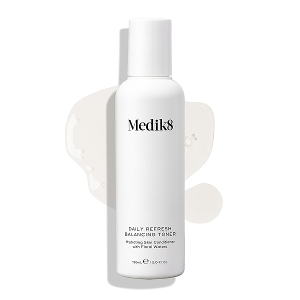 Le flacon de Medik8 Daily Refresh Balancing Toner est présenté sur un fond blanc avec un déversement de liquide clair. Le texte indique qu’il s’agit d’un « Hydrating Skin Conditioner with Floral Waters » de 150 mL.