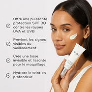 Un modèle tient le tube Medik8 Advanced Day Total Protect à côté d’une liste de bienfaits avec des icônes en forme de coche. Le texte souligne qu’il offre une protection SPF 30 puissante contre les rayons UVA et UVB, prévient les signes visibles de vieillissement, crée une base lissante invisible pour le maquillage et hydrate profondément le teint
