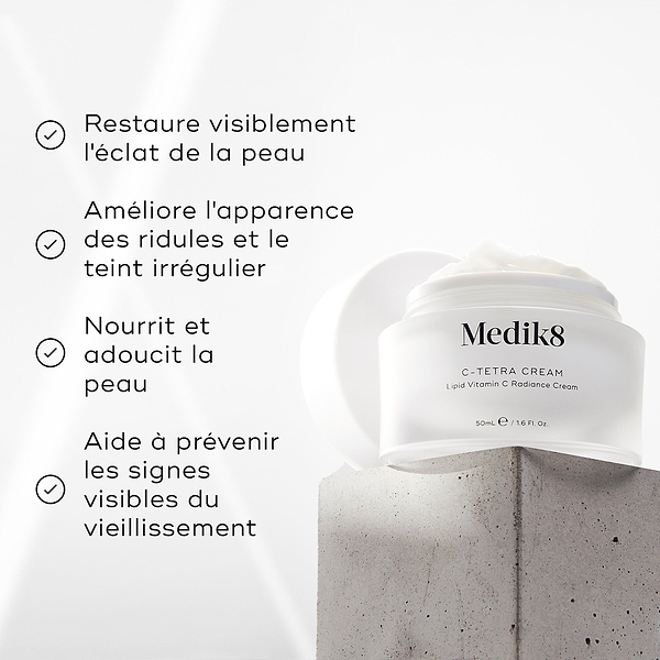 Bocal de crème Medik8 C-Tetra affiché sur un bloc de pierre grise sur fond blanc avec des rayons de lumière douce. L’image présente quatre affirmations avec coche : Restaure visiblement l’éclat de la peau, Améliore l’apparence des ridules et du teint irrégulier, Nourrit et adoucit la peau, Aide à prévenir les signes visibles du vieillissement