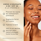 Un modèle à la peau éclatante sourit à côté d’une liste de bienfaits sur un fond doré doux. Le texte met en avant l’hydratant 2-en-1 à la vitamine C avec SPF 30 : Prévient les signes de vieillissement prématuré, stimule l’éclat de la peau, hydrate le teint, 100 % conviennent que leur peau se sent protégée toute la journée