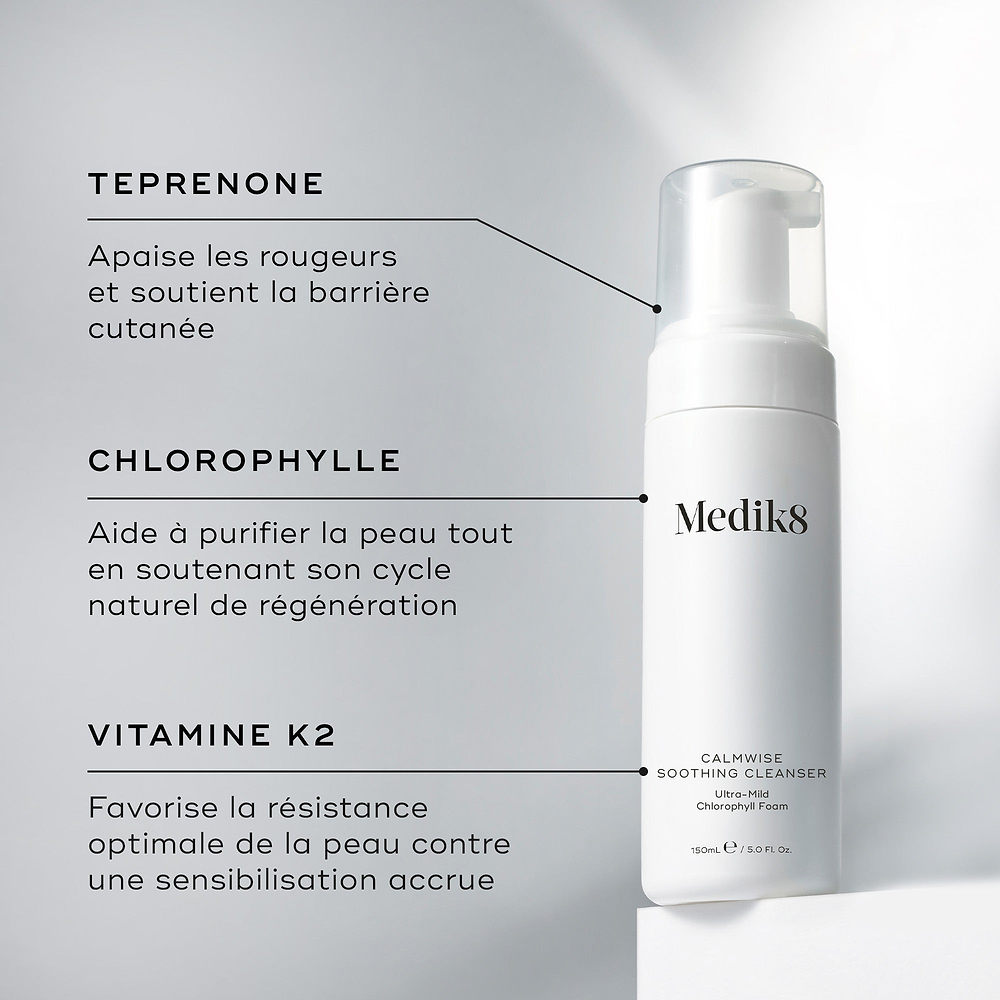 Un flacon de Medik8 Calmwise Soothing Cleanser présenté sur un bloc blanc. Des lignes relient le flacon à un texte expliquant les principaux ingrédients : le téprénone pour apaiser les rougeurs, la chlorophylle pour purifier la peau et la vitamine K2 pour soutenir la solidité de la peau.c
