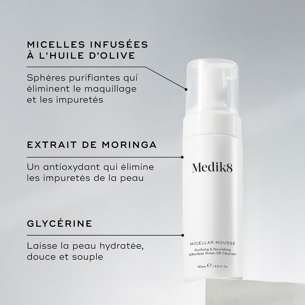 Un flacon de Medik8 Micellar Mousse présenté sur un bloc blanc. Des lignes relient le flacon à un texte expliquant les principaux ingrédients : des micelles infusées à l’huile d’olive pour démaquiller, de l’extrait de moringa pour éliminer les impuretés, et de la glycérine pour hydrater.