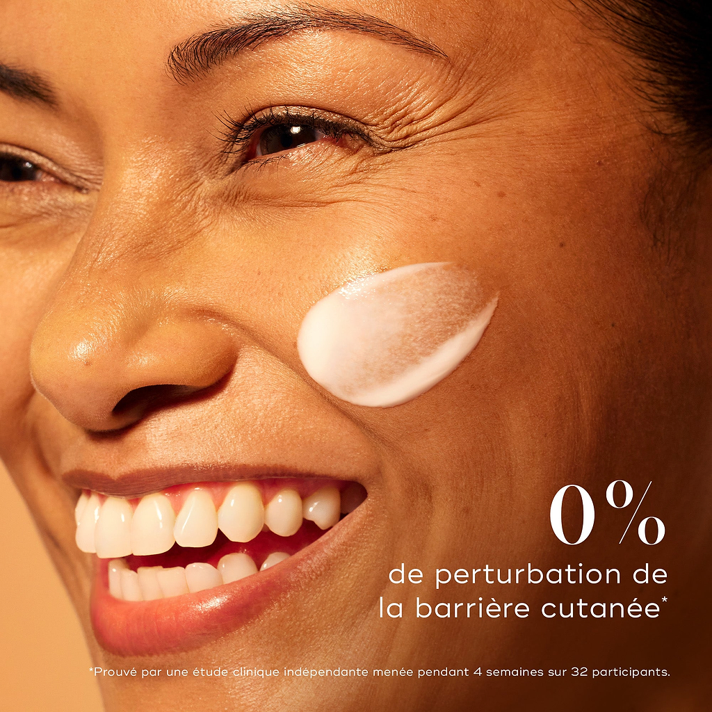 Femme souriante à la peau lumineuse avec une touche de sérum Medik8 C-Tetra Advanced sur la joue, mettant en avant 0 % de perturbation de la barrière cutanée pour un éclaircissement doux mais efficace.