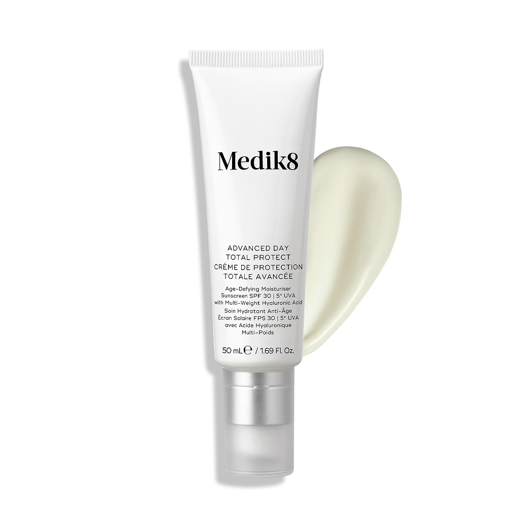 Tube Medik8 Advanced Day Total Protect présenté sur un fond blanc propre avec une large trace de crème hydratante blanche. Le texte l'identifie comme un Age-Defying Moisturiser avec SPF 30 et protection UVA 5* en 50 mL