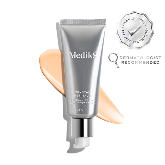 Tuba Medik8 Crystal Retinal 6 spočívá na stopě světle růžového séra na bílém pozadí. Odznaky zdůrazňují „vítěz Get The Gloss Beauty Awards 2025“ a „první patentovaná technologie na světě“, spolu s textem uvádějícím *„č. 1 dermatologické pleťové sérum ve Velké Británii“**.-hover-3