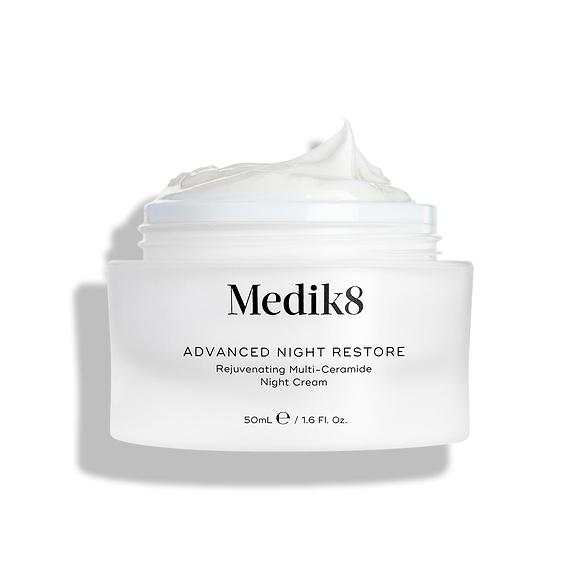 Medik8 Advanced Night Restore Cremetiegel geöffnet mit einer reichhaltigen Spitze weißer Creme obenauf vor einem sauberen weißen Hintergrund, der die geschmeidige, regenerierende Textur hervorhebt. Schwarzer Text auf dem Tiegel lautet Rejuvenating Multi-Ceramide Night Cream.-4