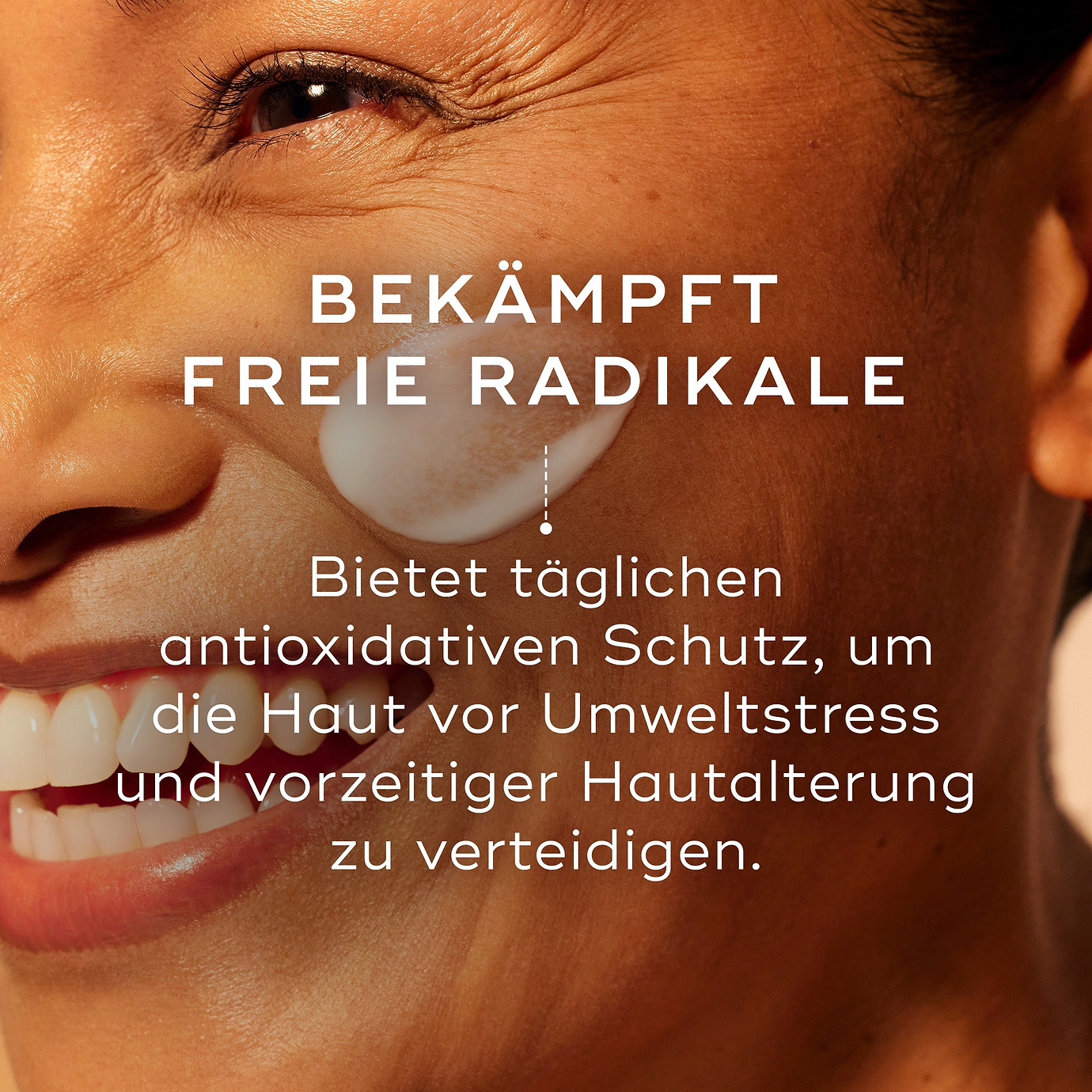 Nahaufnahme eines lächelnden Gesichts, auf dessen Wange ein weißer Cremeklecks aufgetragen ist. Der Text lautet: 